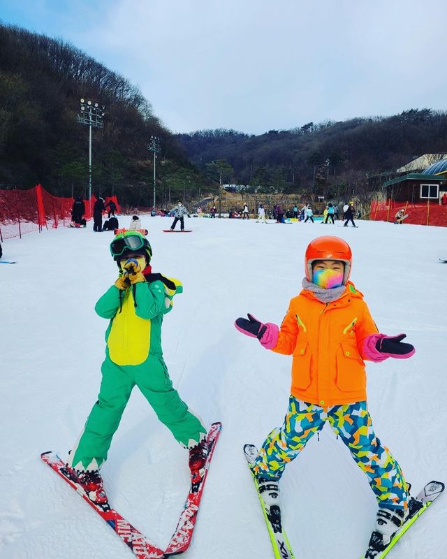 초급 슬로프에서 스키를 신고 포즈를 취한 두 어린이